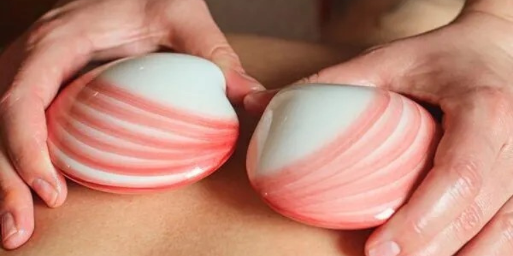 Coral pink and cream painted ceramic shells are being used in a Hot Stone Massage.